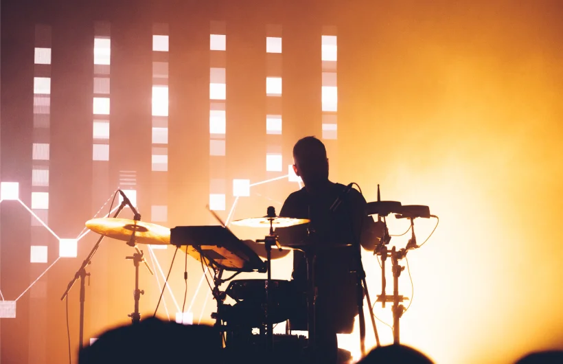 Jiří of Bratři playing live drums in orange stage light